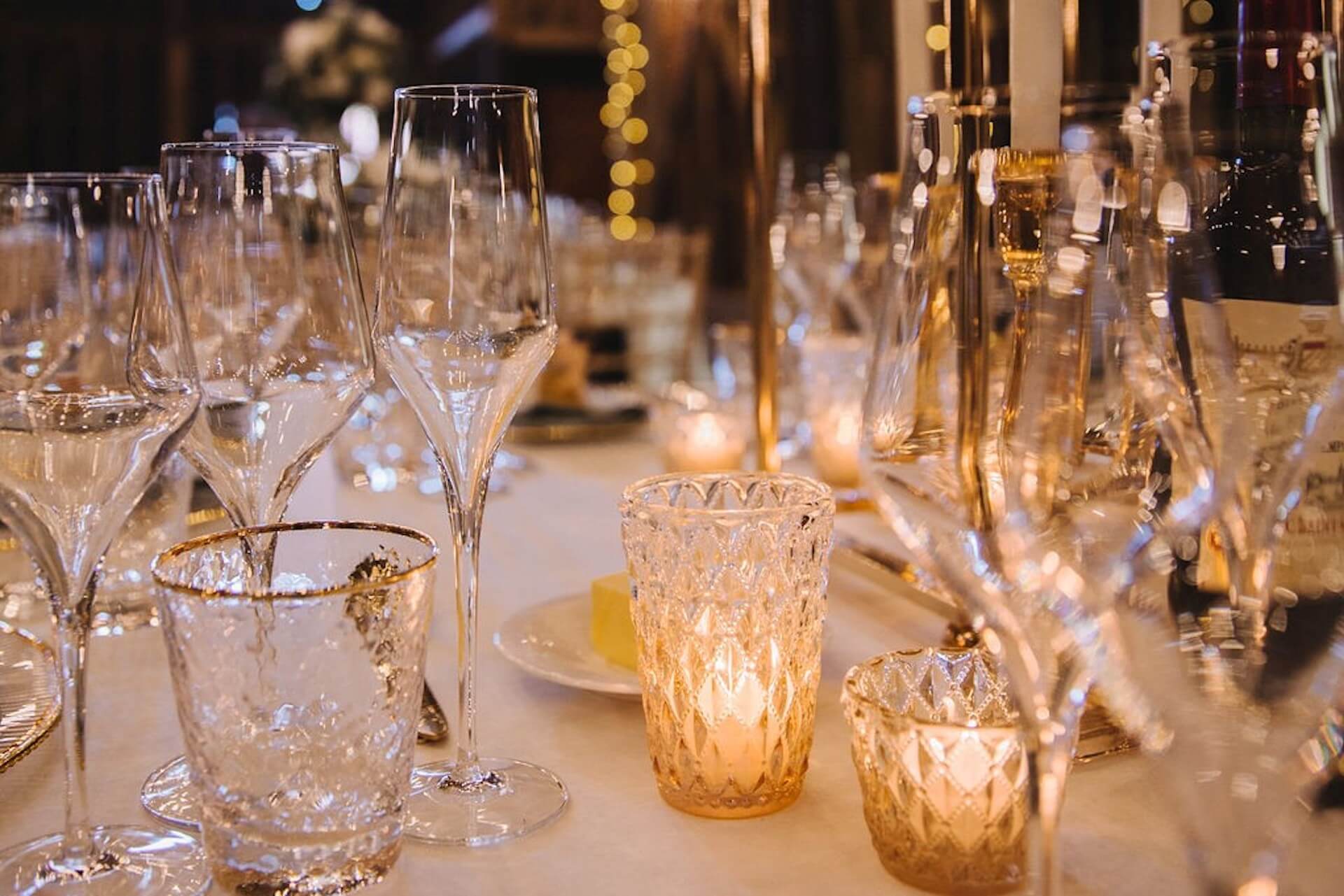 Elegant wedding reception table with champagne glasses, sparkling glassware and warm candlelight creating an intimate atmosphere.