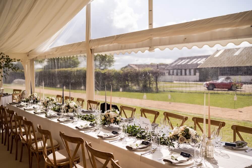 Long dining tables set for an English countryside marquee wedding